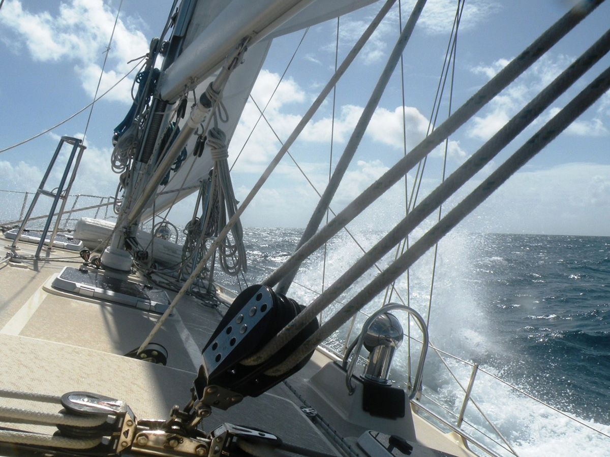 Water spraying onto the deck of a heeling sailboat on a sunny day